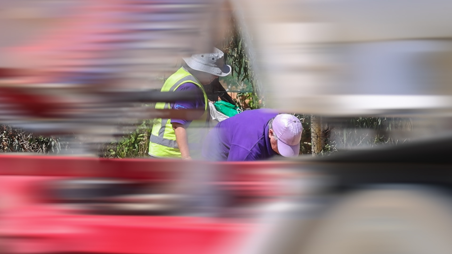 Um trem rodoviário passa por três pessoas coletando lixo na beira da estrada.