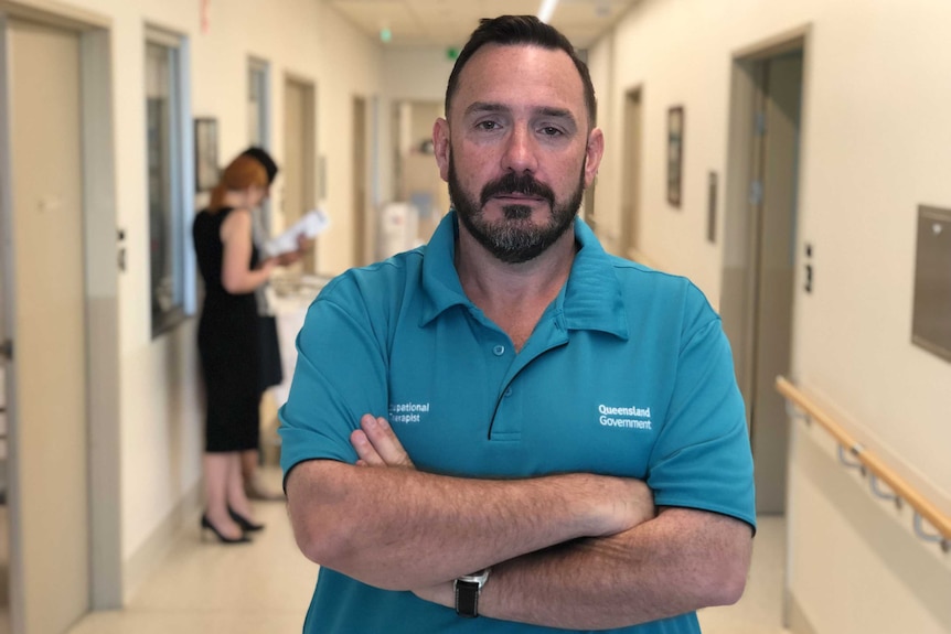 Occupational therapist Russell Plumbridge-Jones stands in a corridor at Robina Hospital with his arms folded.