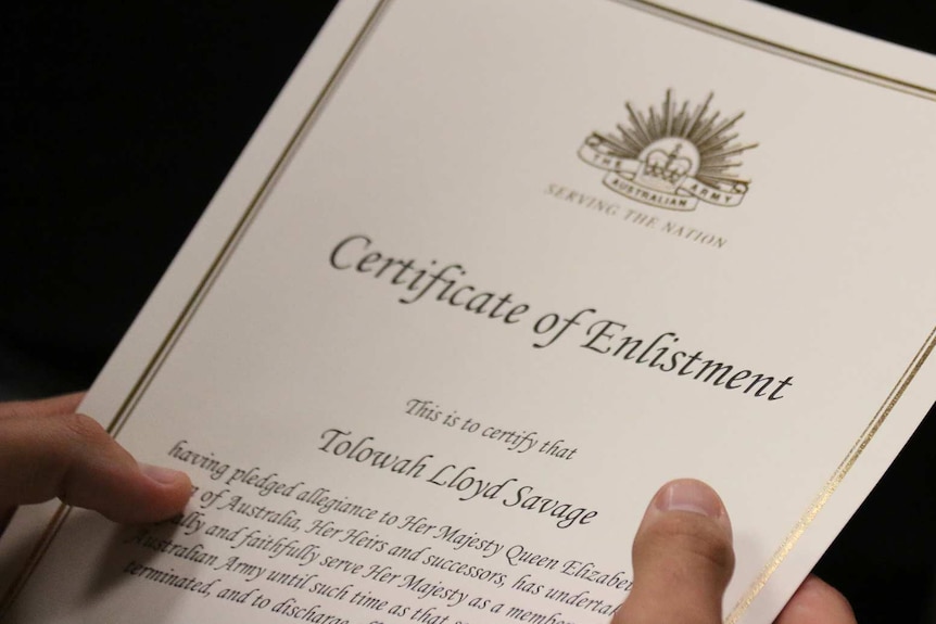A recruit holds his Certificate of Enlistment at the Army enlistment ceremony in Darwin.