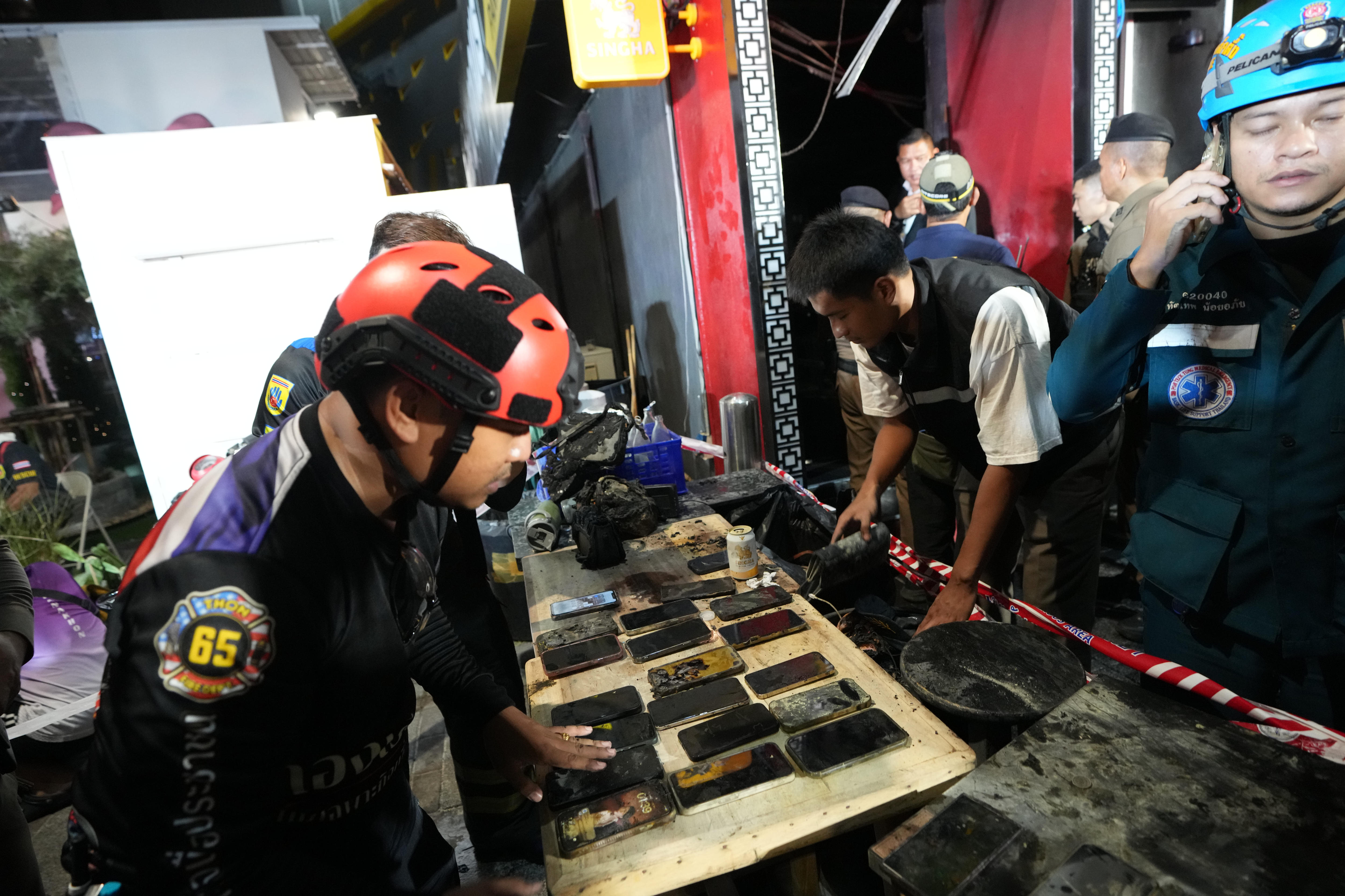 First responders stand around a table covered with charred phones.