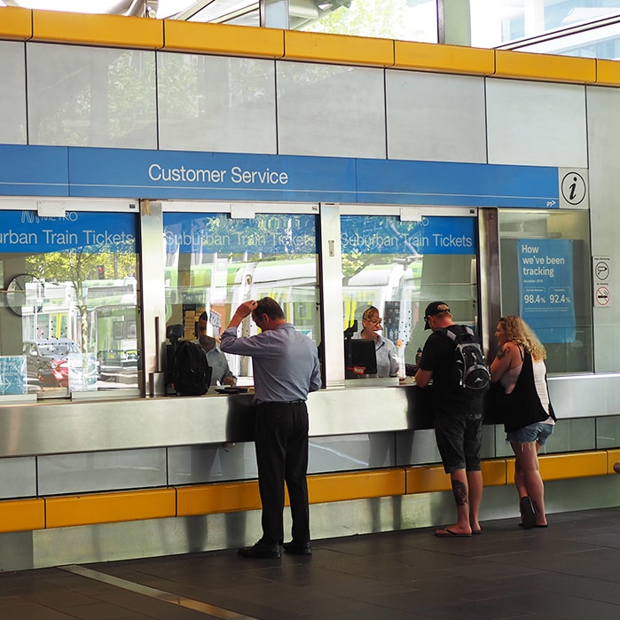 Three people at the customer service windows at Southern Cross train station.