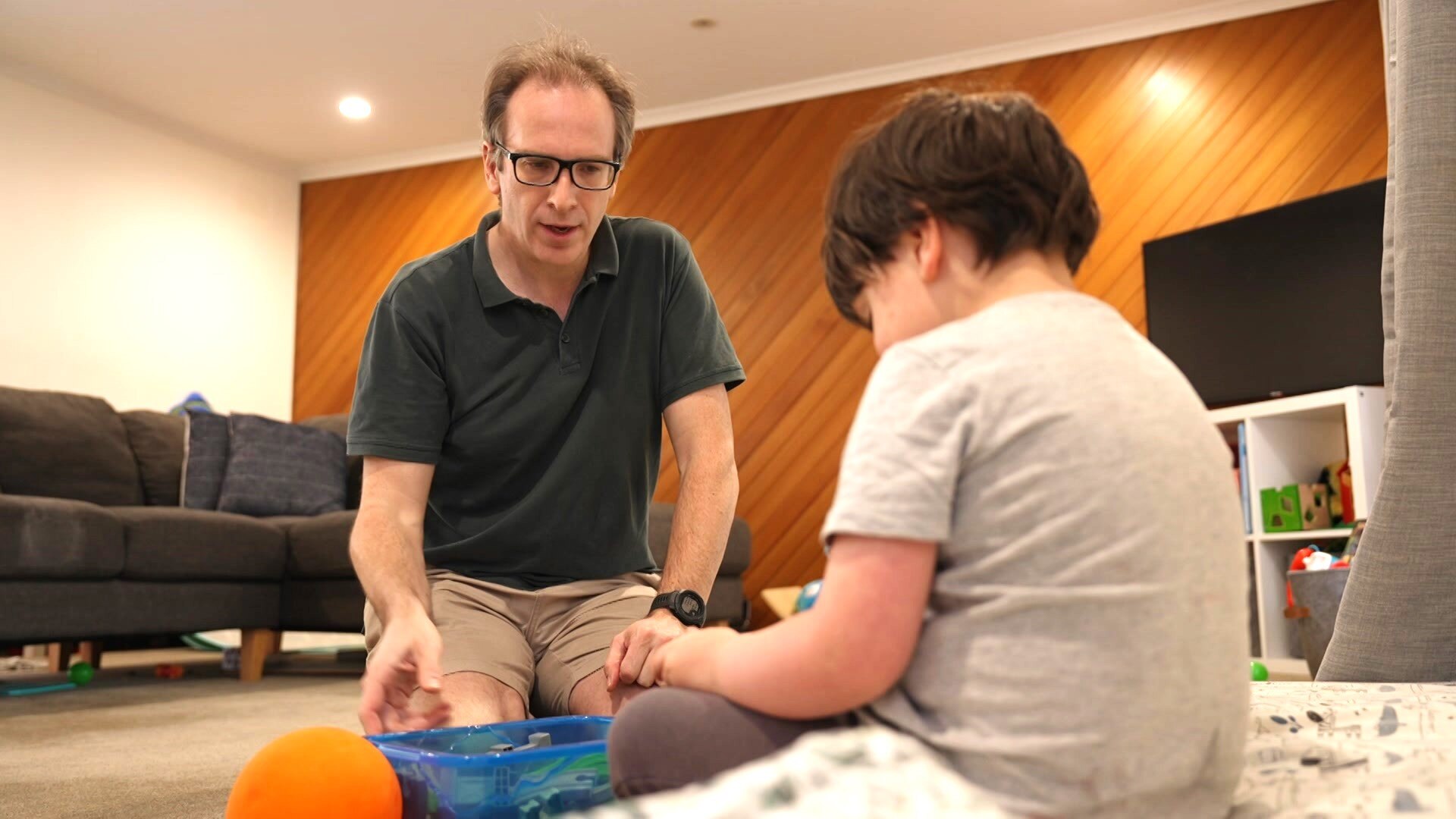 Father and his five-year-old son playing with toys in their loungeroom. 