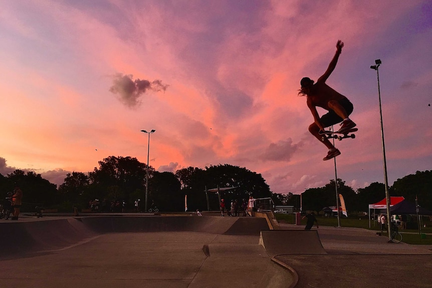 skateboarder jumping in the air at dusk