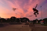 skateboarder jumping in the air at dusk