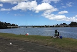 A recreational fisher sits on a chair at the shore of the Shoalhaven River at Nowra.