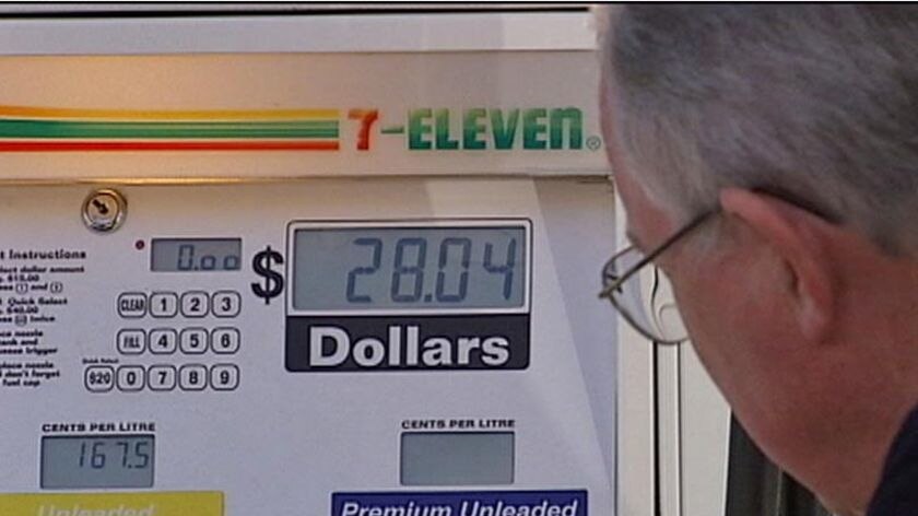 Man looks at price while pumping petrol
