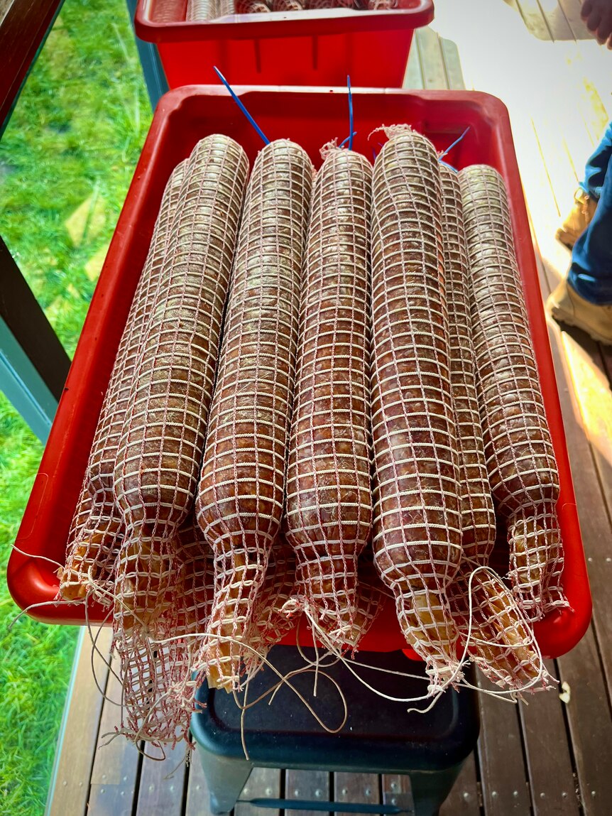 A red bucket full of hand tied salami