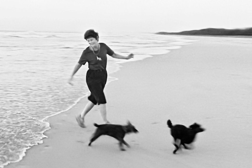 Diana walking on the beach with her dogs