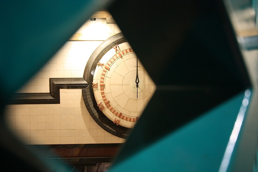 A clock strikes 12:00 at an unidentified railway station.