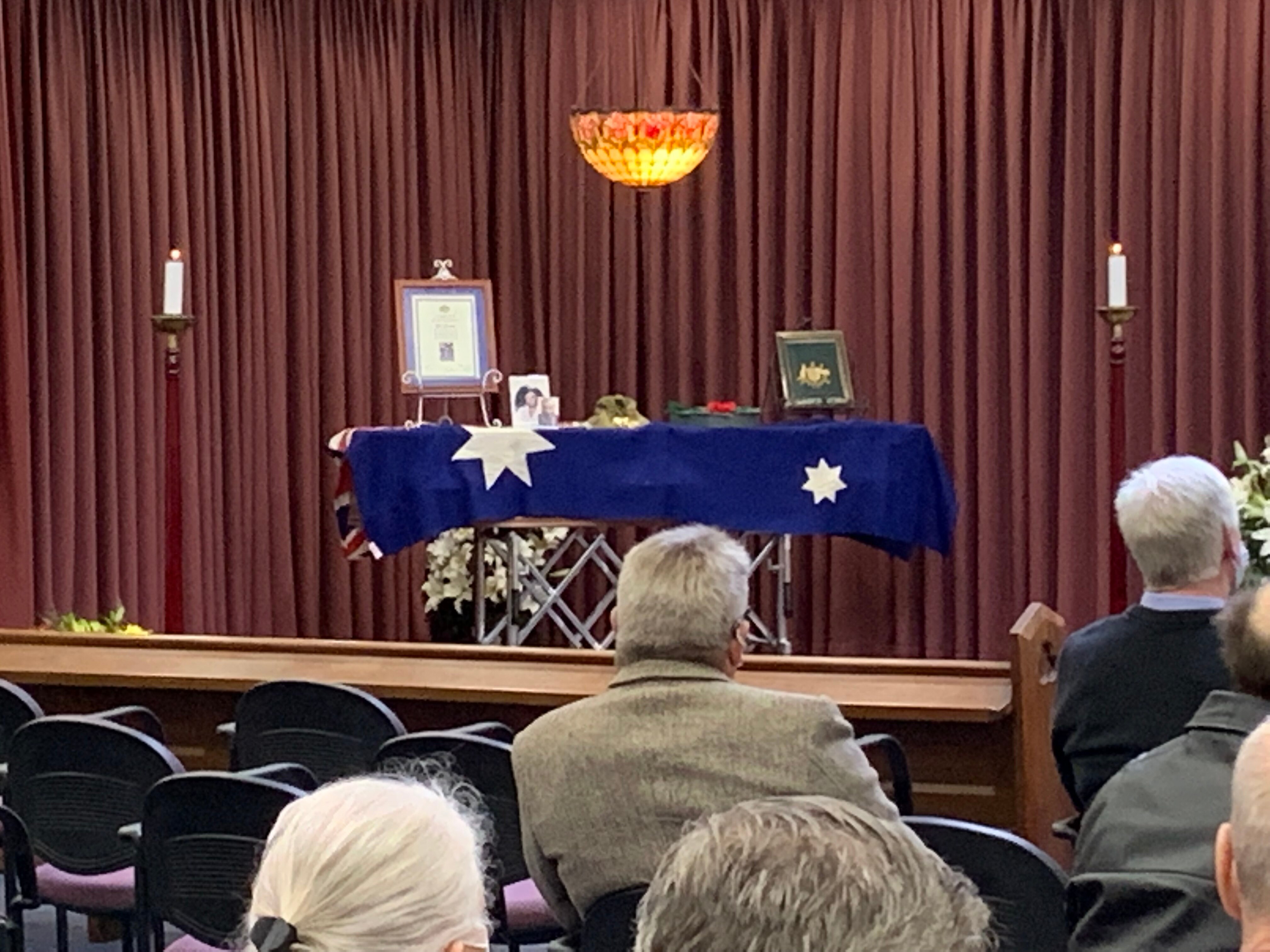 A coffin draped with the Australian flag and pictures.