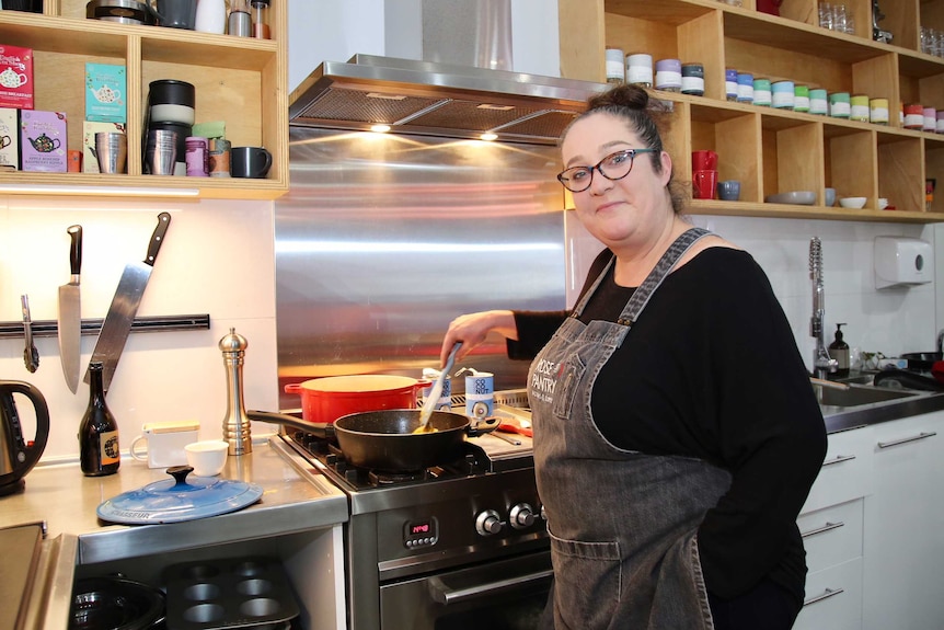 Meridith Stevens stirs food cooking in a pan on an oven in her shop in Fitzroy.