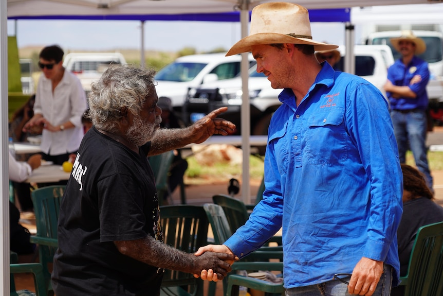 A pastoralist and Anangu man shake hands