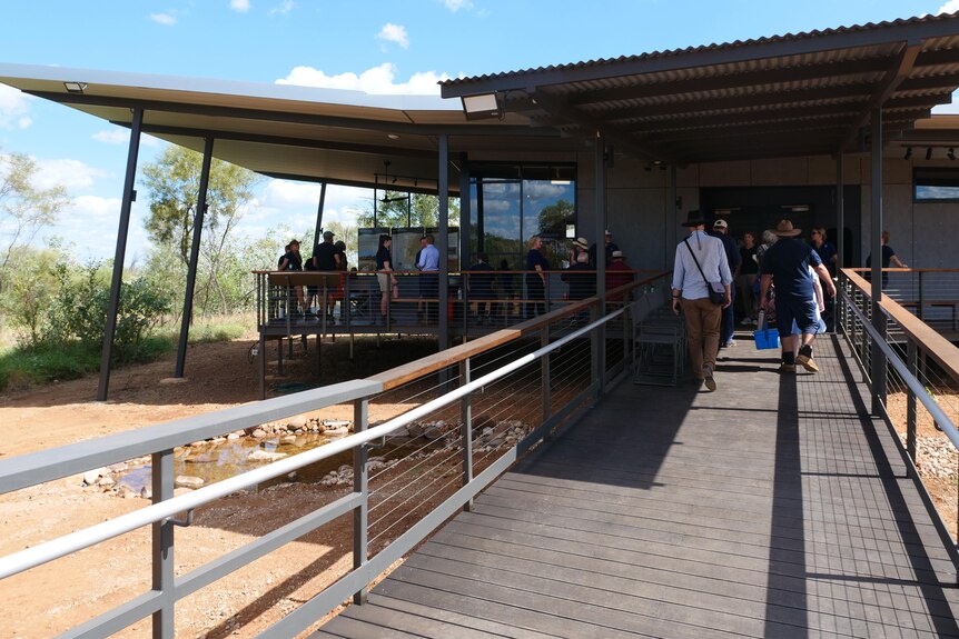 a visitor centre, a black building with a deck, surrounded by scrub