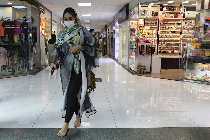 A woman wearing a protective face mask walks through a shopping centre in Tehran, Iran.