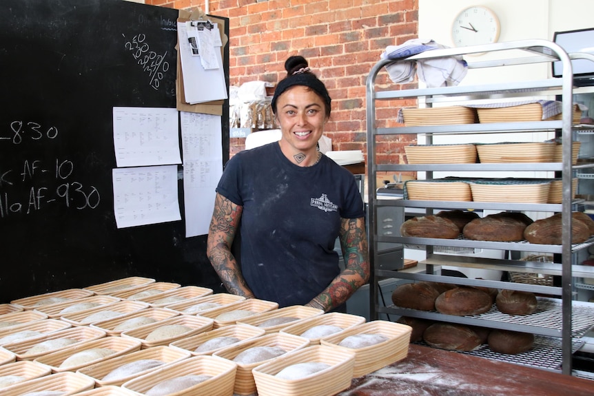 Chantal stands in front of loaves of bread.