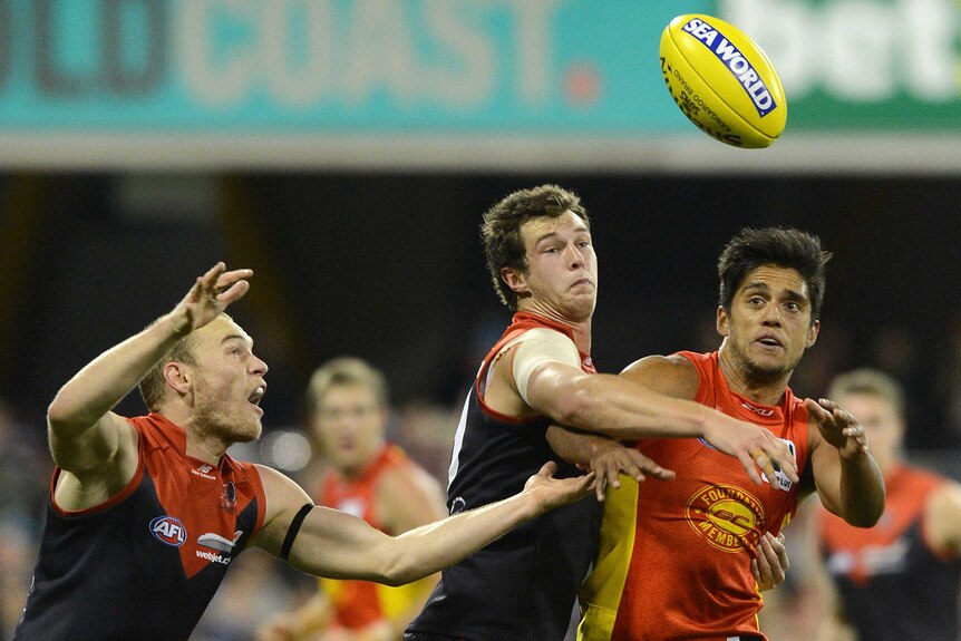 The Demons' James Strauss (C) competes with the Suns' Aaron Hall (R) at Carrara.