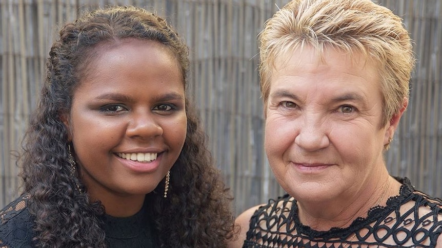 A young Indigenous woman and a middle-aged non-Indigenous woman smile at the camera.
