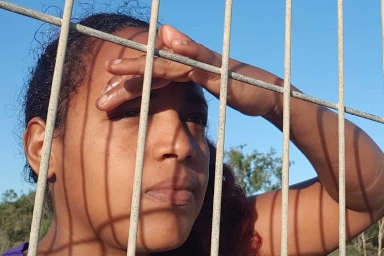 A woman behind behind a wired fence.