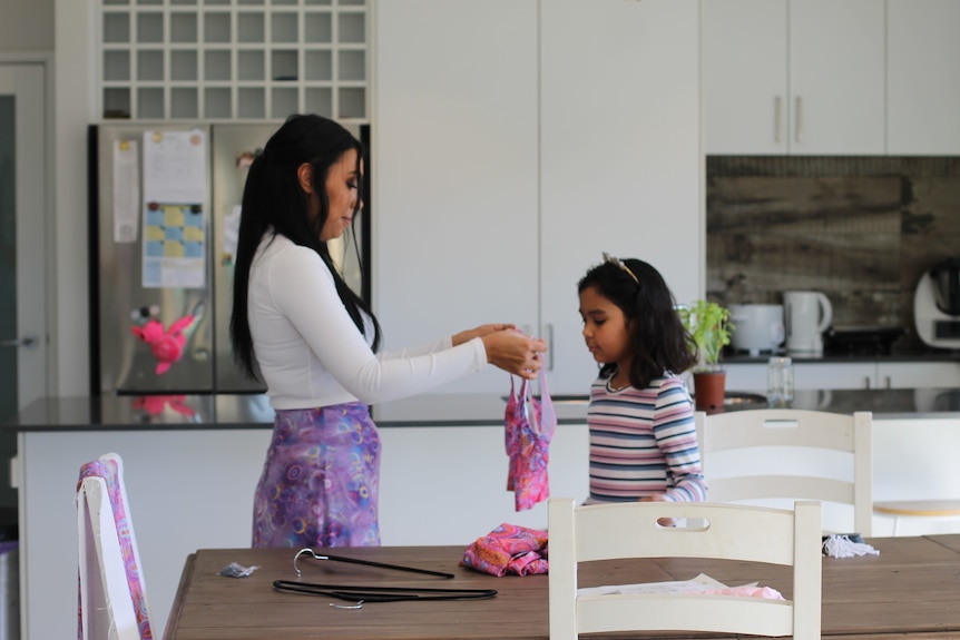 A woman holds designs with a child 