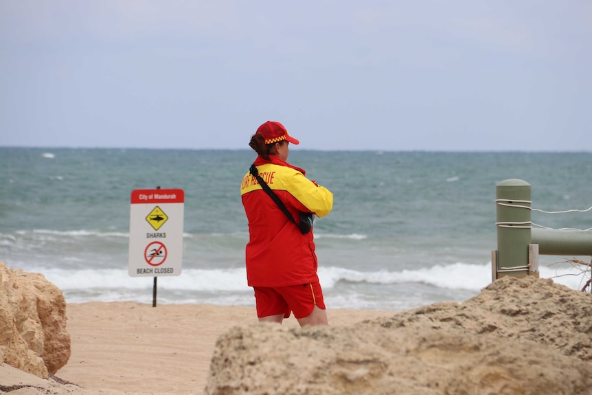 A surf lifesaver at Pyramids Beach stares at the ocean.