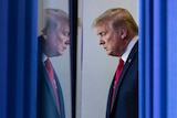 Donald Trump waiting behind a blue curtain looking serious