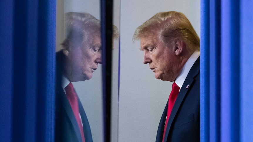 Donald Trump waiting behind a blue curtain looking serious