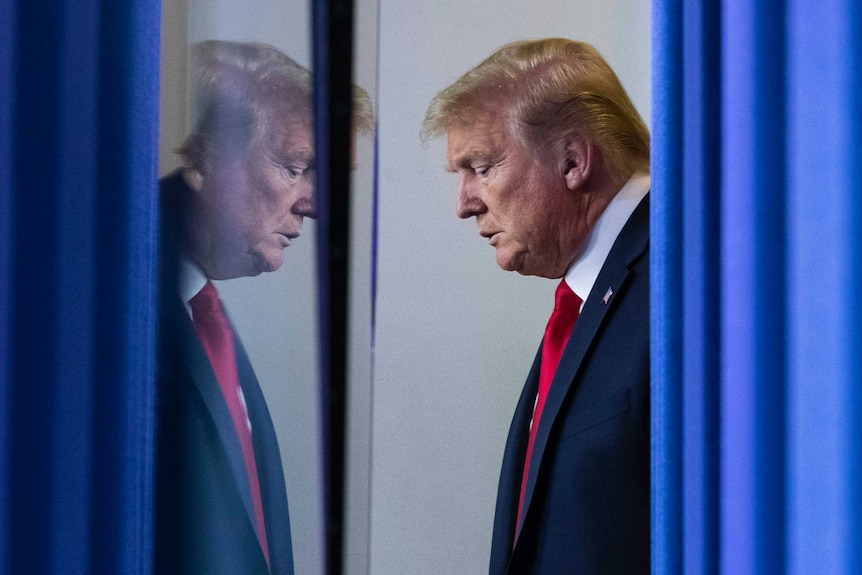 Donald Trump waiting behind a blue curtain looking serious