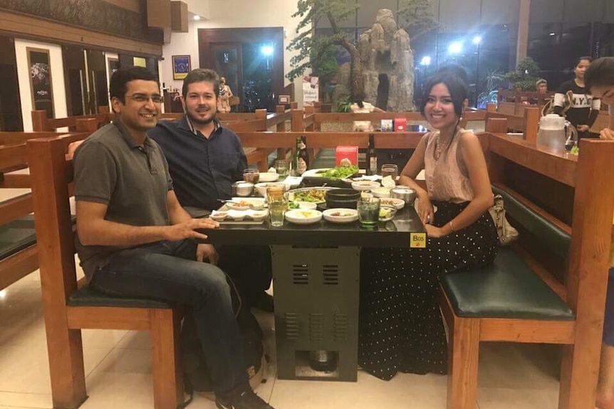 Cambodian opposition leader Kem Sokha's daughter sits at a dinner table with American journalist Geoffrey Cain and one other man