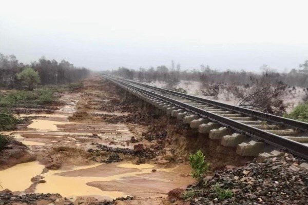 A stretch of railway line with mud and puddles beside it.