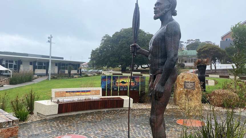 A statue of an Indigenous man in the centre of a park 