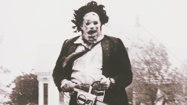 A black and white still from the film shows a man wearing a suit and mask carrying a chainsaw.