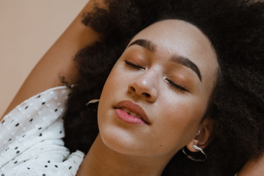 Peaceful young black woman relaxing with closed eyes