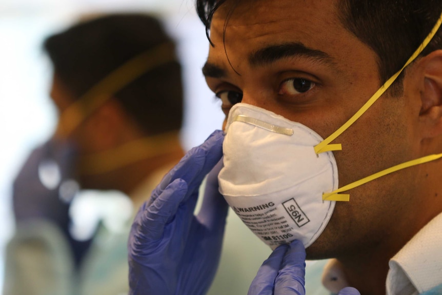 Melbourne GP Vyom Sharma looks into the camera while wearing a facemask.