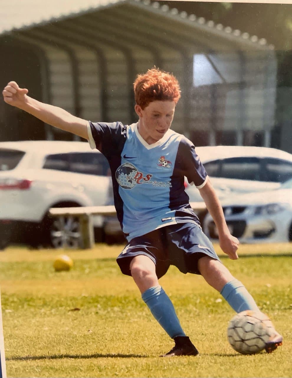 a young boy in a football jersey kicks a soccer ball