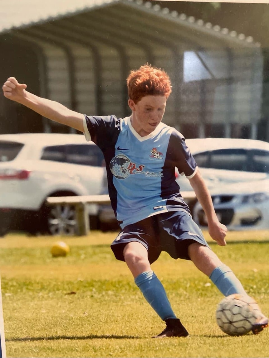 a young boy in a football jersey kicks a soccer ball