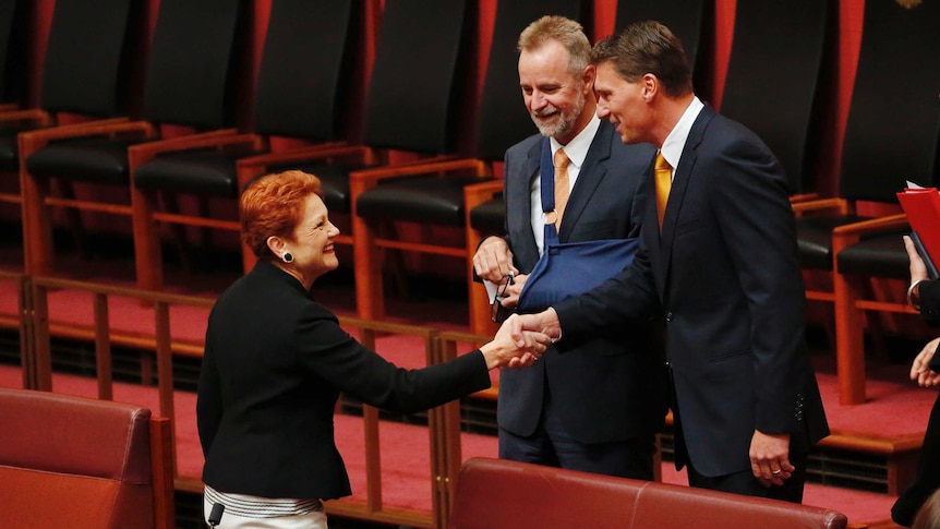 Cory Bernardi shakes hands with Pauline Hanson in the Upper House, Nigel Scullion looks on