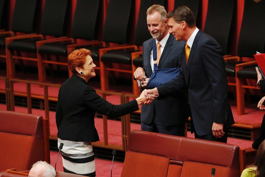 Cory Bernardi shakes hands with Pauline Hanson in the Upper House, Nigel Scullion looks on