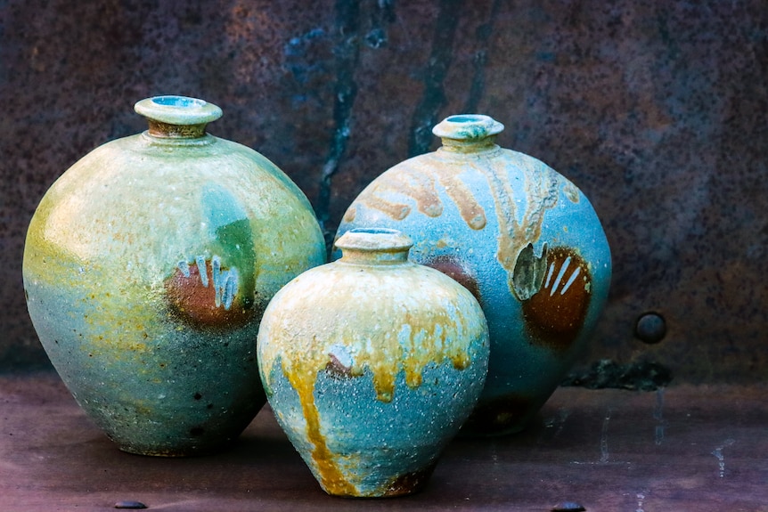 Three pots with the imprints of shells and markings of woodflire glazing dribbling from the top.