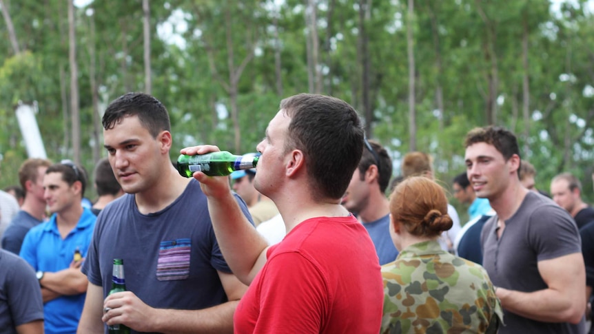 A man swigs beer from a bottle.