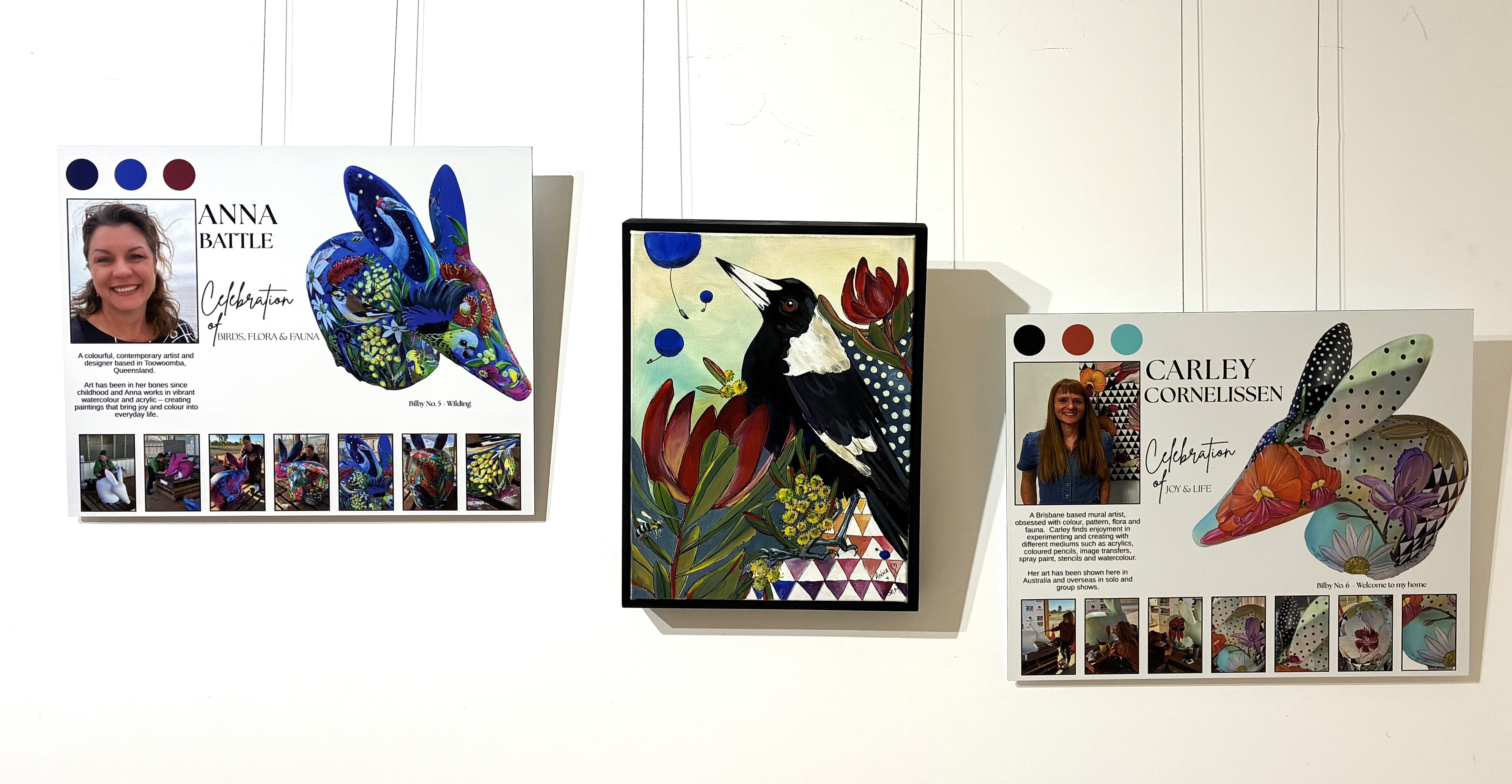 two artist profiles of bilby painters hanging either side of a painting of a magpie