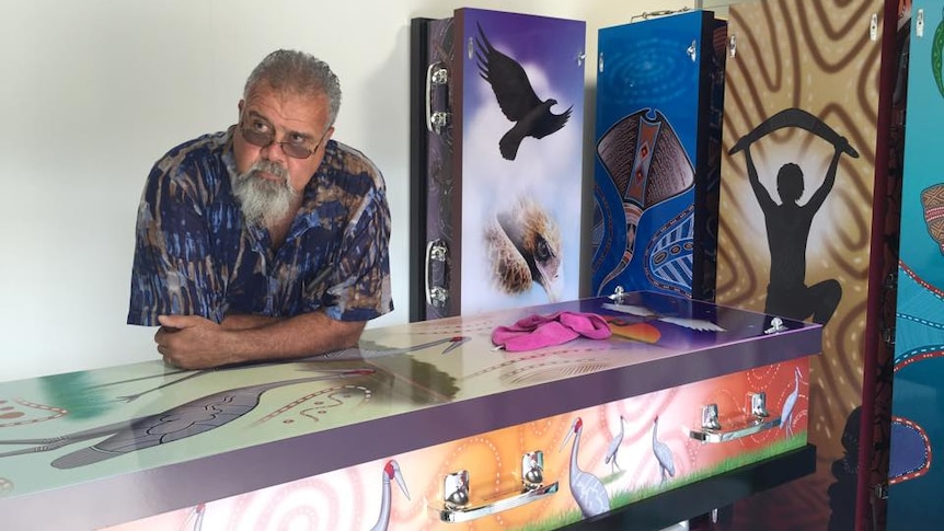 Funeral service owner stands with his coffins which carry indigenous designs