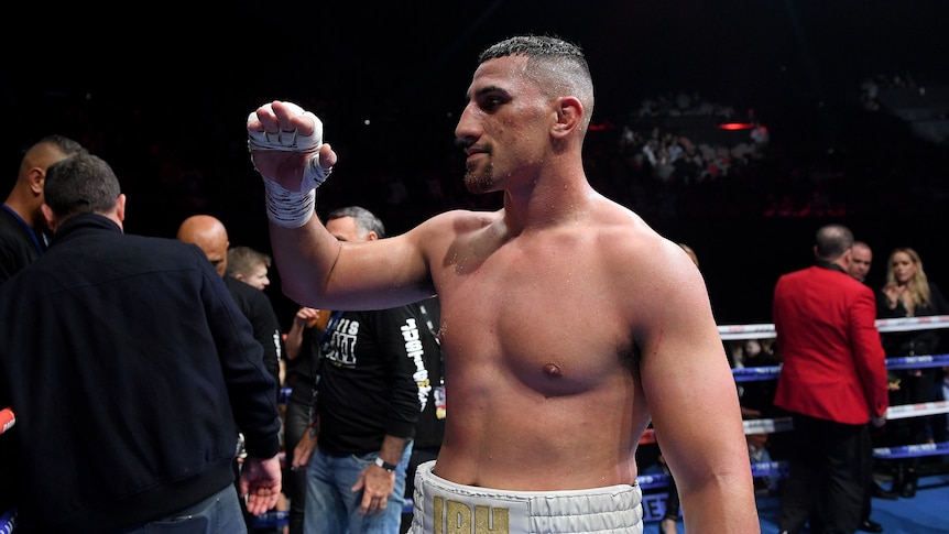 Boxer Justis Huni holds his taped right hand up while standing in the ring after beating Paul Gallen in their fight.