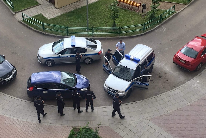 View from above of Russian opposition politician Alexei Navalny hopping in police car surrounded by officers