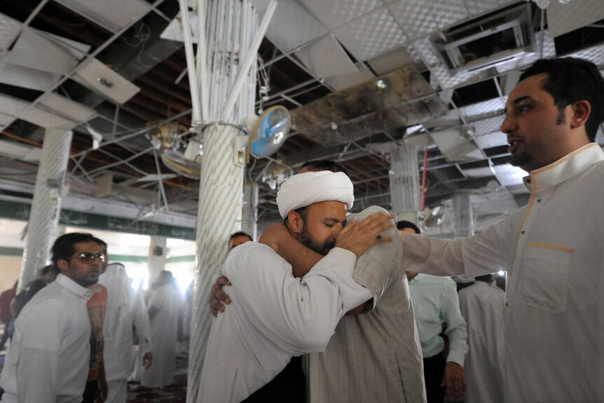 Two Saudi men embrace in the Shiite mosque.