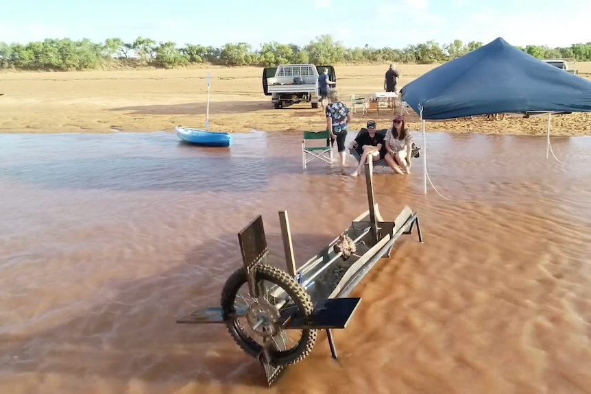 A rotisserie sitting in the Gascoyne river with people nearby