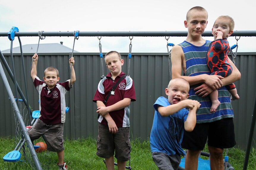 five boys standing in front of a wet swing set