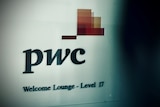 Black letters that spell out PwC on a white wall with red, orange and yellow graphic squares above the letter C.