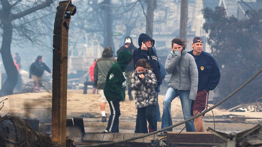 People stand among homes destroy by fire at Breezy Point