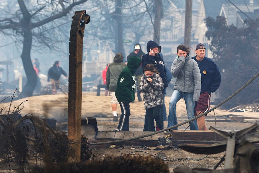 People stand among homes destroy by fire at Breezy Point