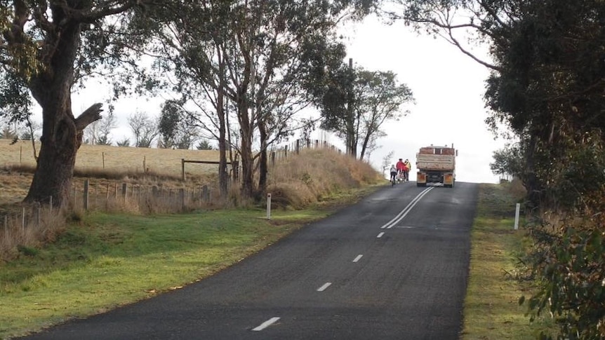 A photo of cyclists on the road next to a truck 